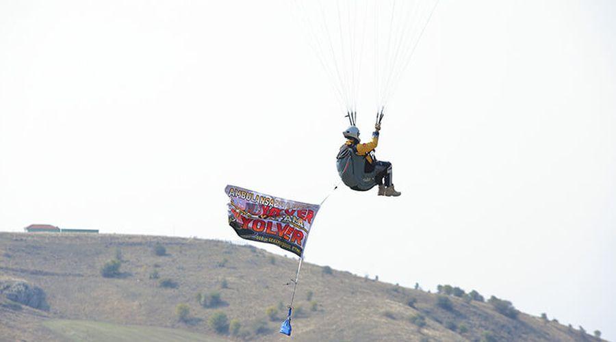 Acil tıp teknisyeni yamaç paraşütünden açtığı afişle ambulanslara yol istiyor